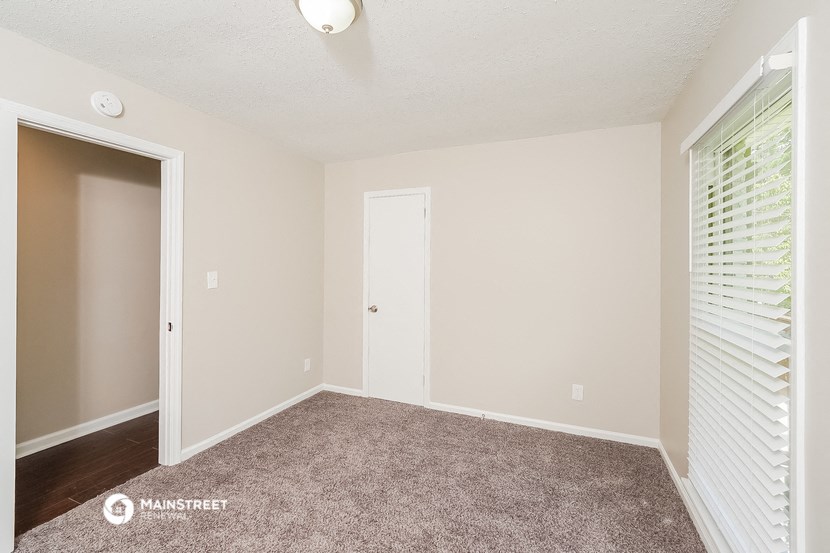 a bedroom with a carpeted floor and a door to a closet
