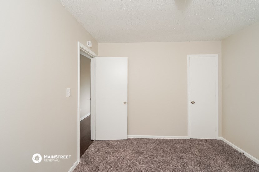 a bedroom with a carpeted floor and a door to a closet