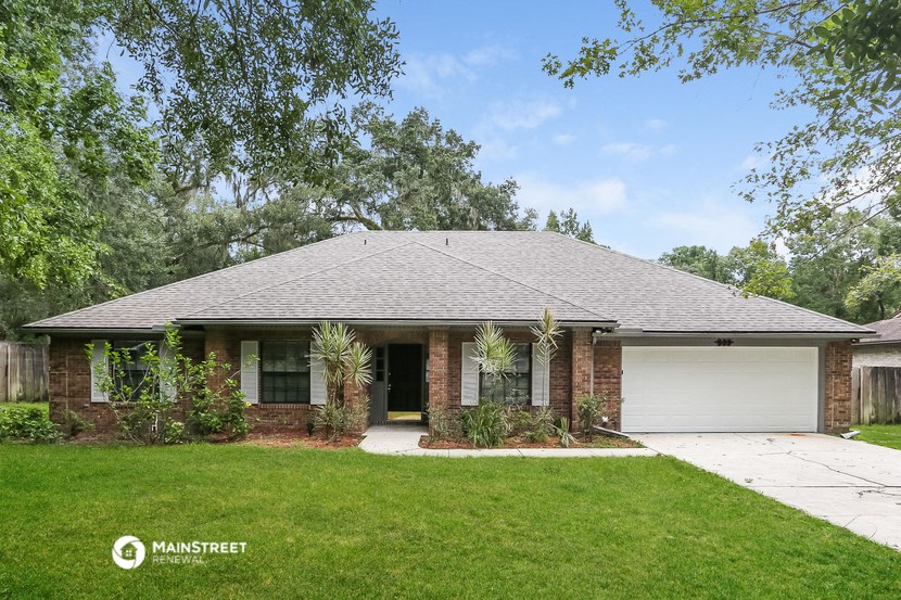 front view of a brick house with a lawn and trees