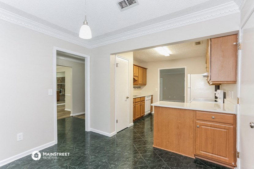 a kitchen with wood cabinets and a white counter top and a door to a hallway