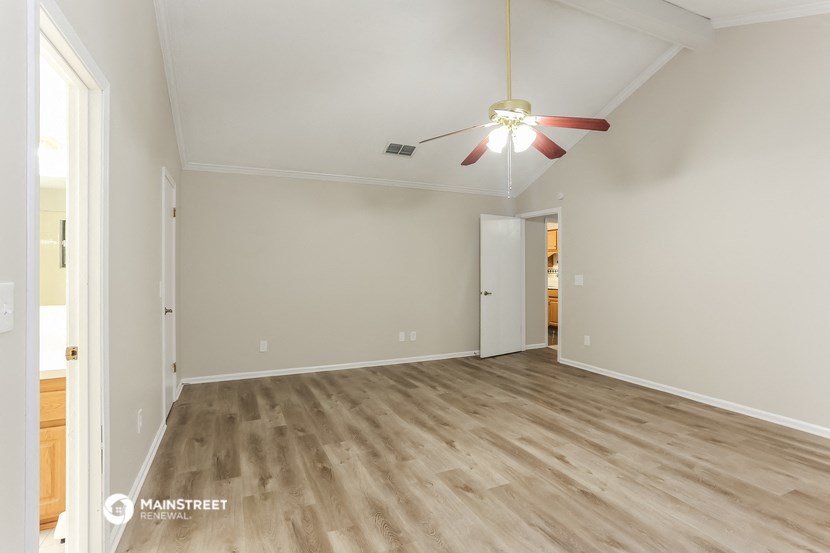 the living room of an empty house with wood flooring and a ceiling fan