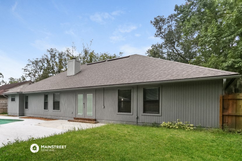 the front of a gray house with a lawn and a driveway