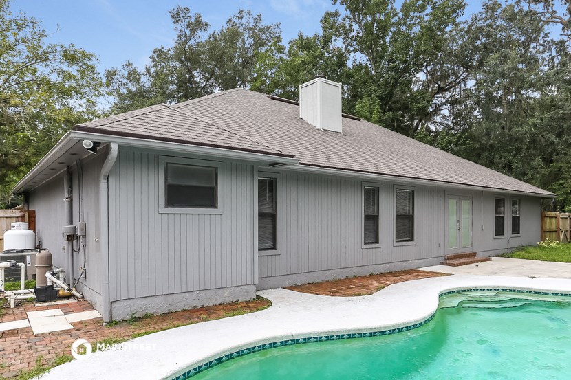a small gray house with a pool in front of it