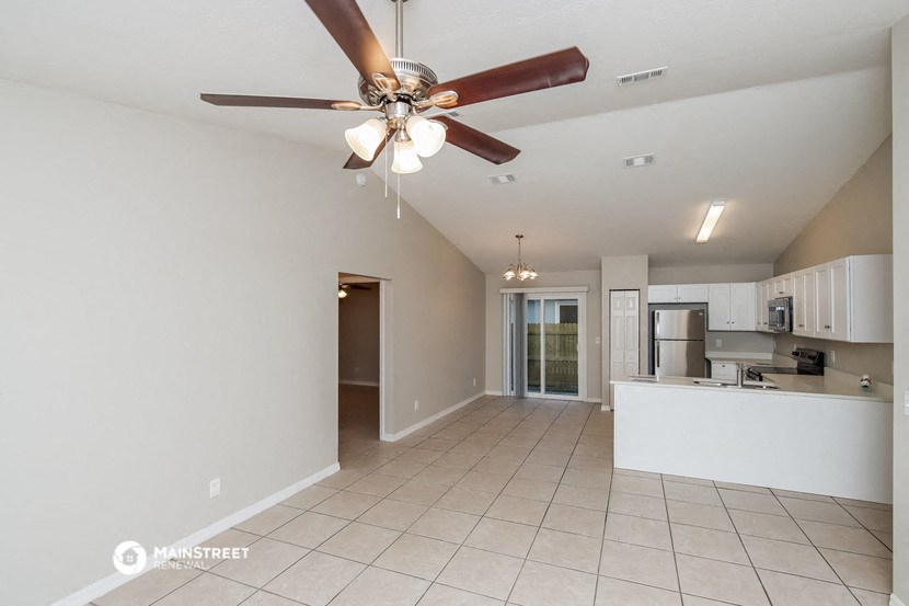 an empty living room and kitchen with a ceiling fan