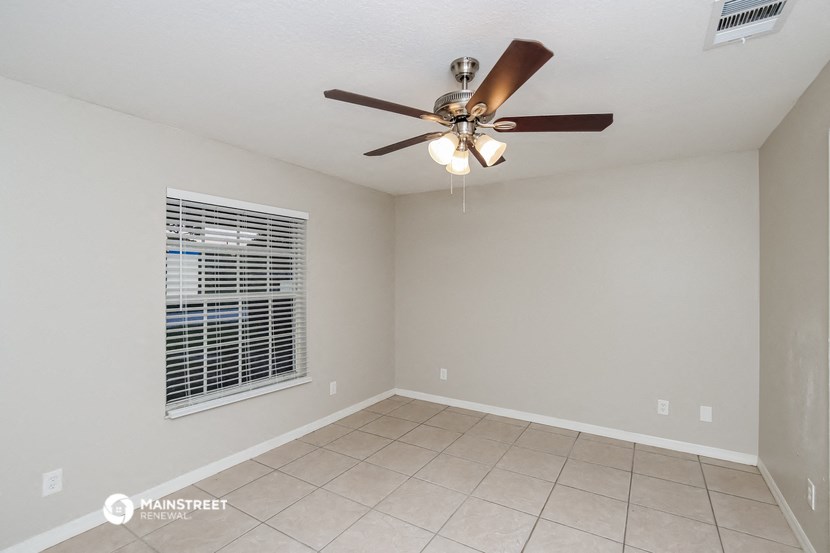 the living room has a ceiling fan and a tiled floor