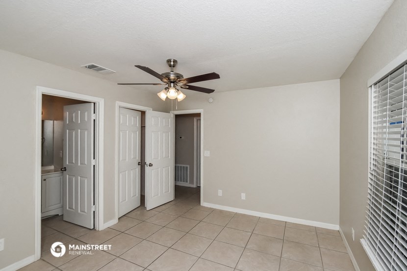 the living room has a ceiling fan and tile flooring
