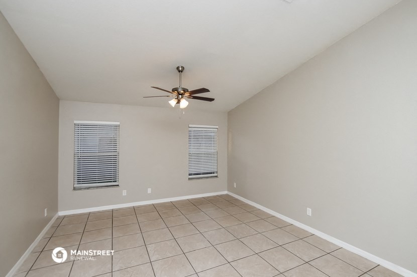 the spacious living room has a ceiling fan and tile flooring
