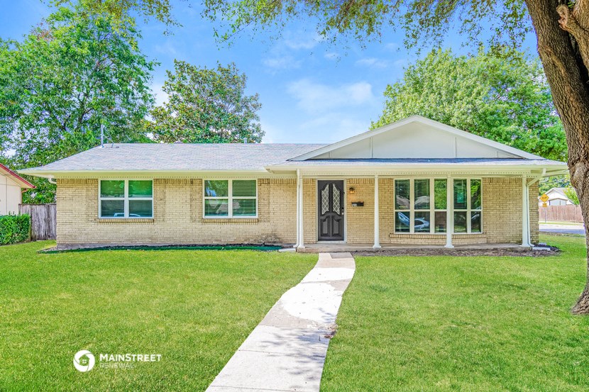 a small brick house with a lawn and trees