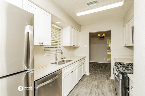 a white kitchen with stainless steel appliances and white cabinets
