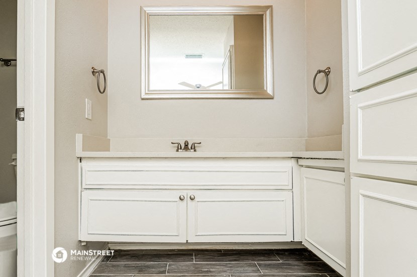 a bathroom with white cabinets and a sink and a mirror