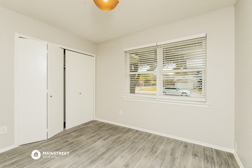 the spacious living room with a large window and wood flooring