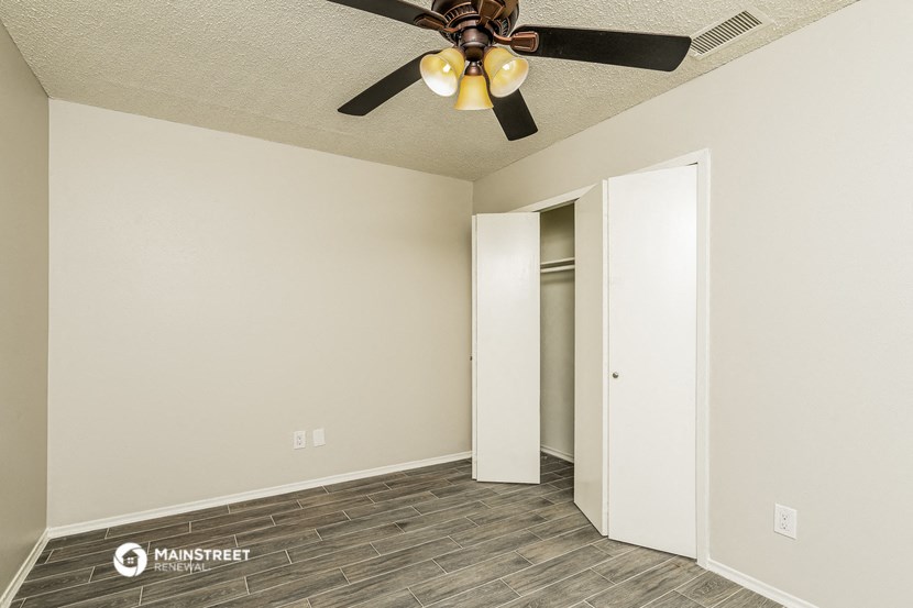 the spacious living room with ceiling fan and closet