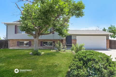 a home with a lawn and a tree in front of it