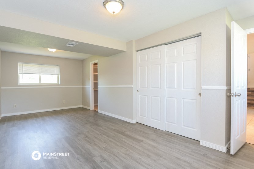 an empty living room with a door to a closet and a window