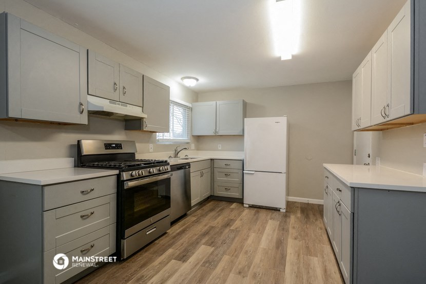 an empty kitchen with white cabinets and stainless steel appliances
