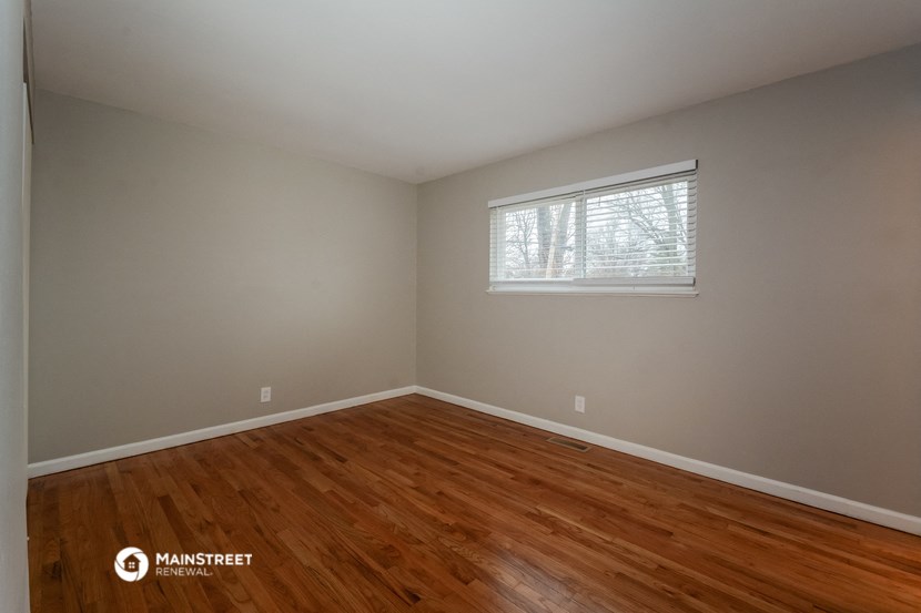the bedroom with hardwood floors and a window