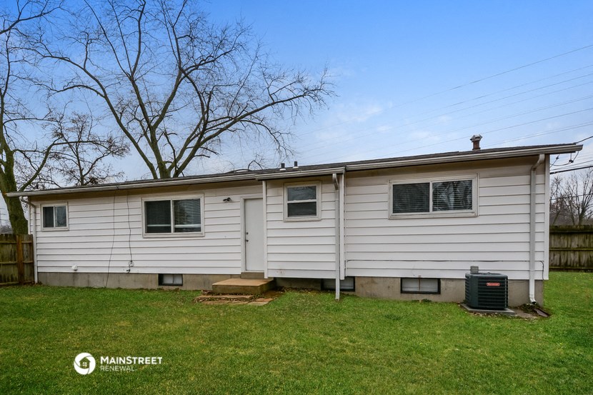 the front of a white house with a yard and a tree
