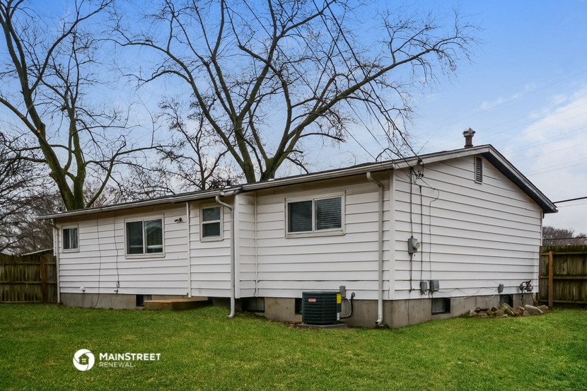 the front of a white house on a lawn with trees
