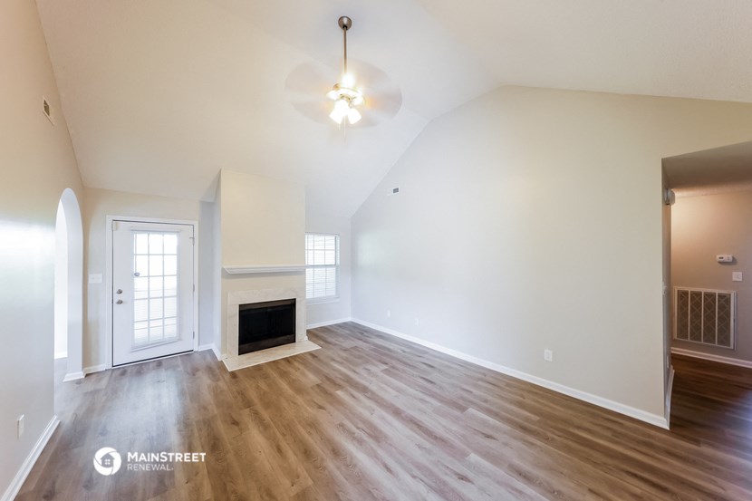the living room of a house with white walls and a fireplace