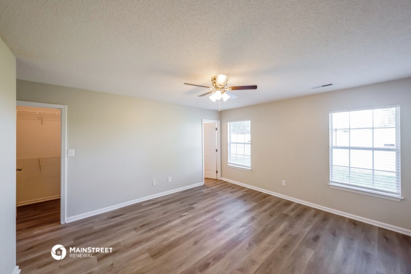 the spacious living room with hardwood flooring and a ceiling fan