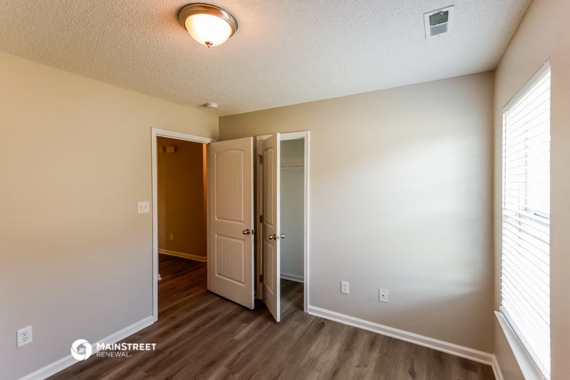 the spacious living room of an apartment with a door open to the hallway