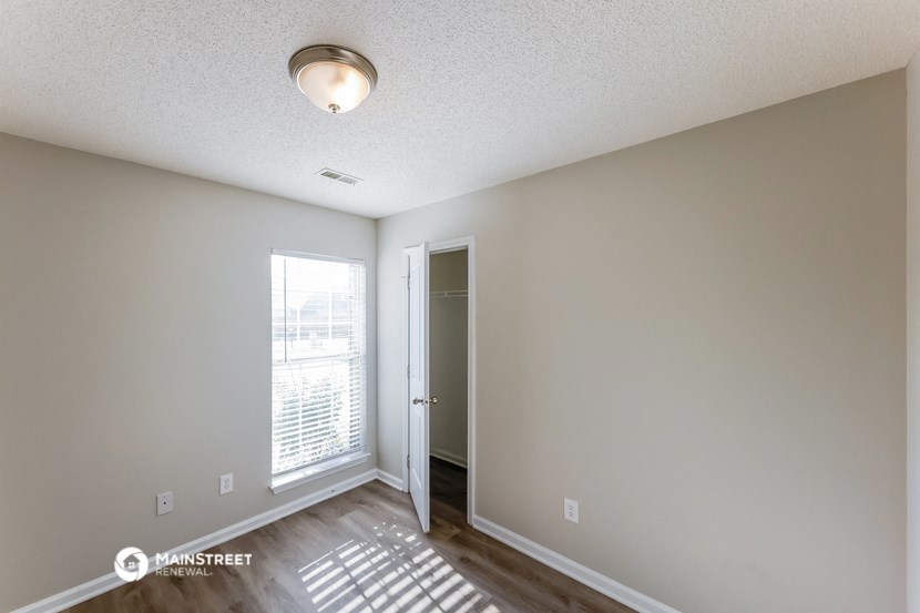 the living room of an apartment with a window and a door to a hallway