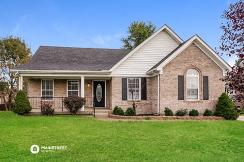 a brick house with black shutters and a green lawn