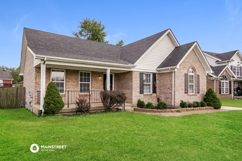 a brick house with white siding and a yard with green grass