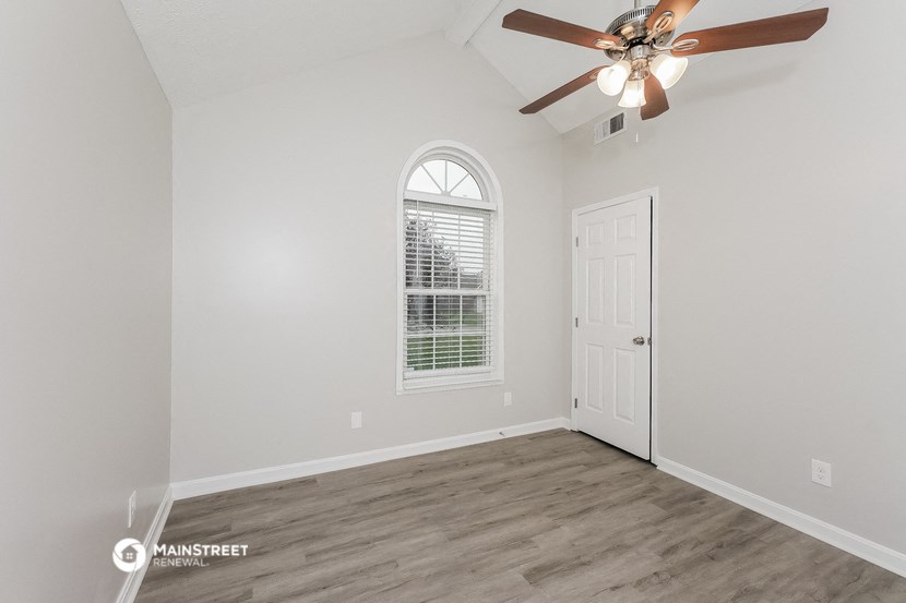 the living room of a home with white walls and a ceiling fan