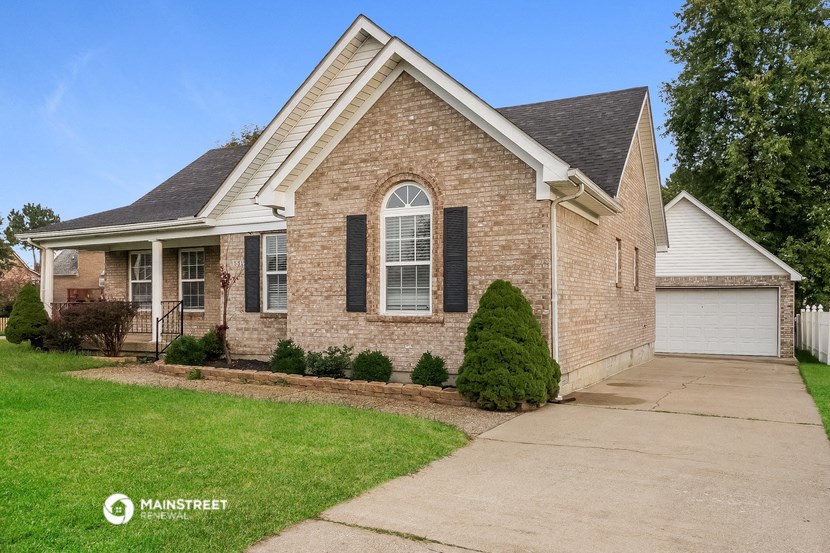 a brick house with black shutters and a driveway