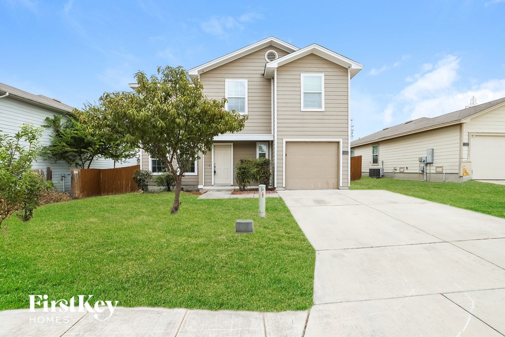 A house with a garage and a driveway in front of it.