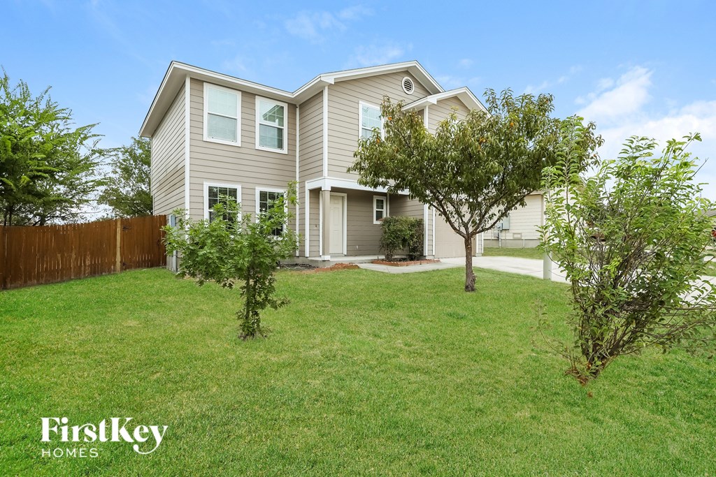 A house with a fence and trees in the front yard.