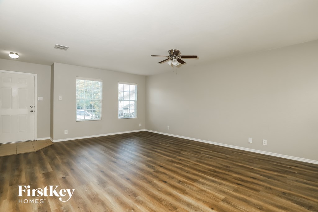 A spacious room with wooden floors and a ceiling fan.