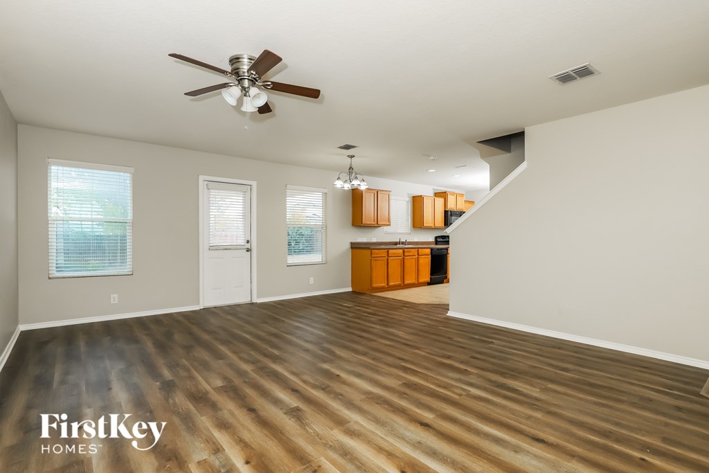 A spacious room with wooden floors and a ceiling fan.