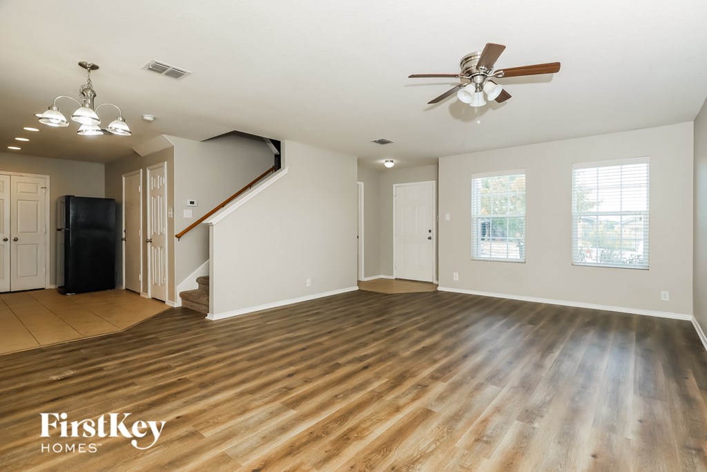 A spacious room with wooden floors and a staircase leading to the upper level.