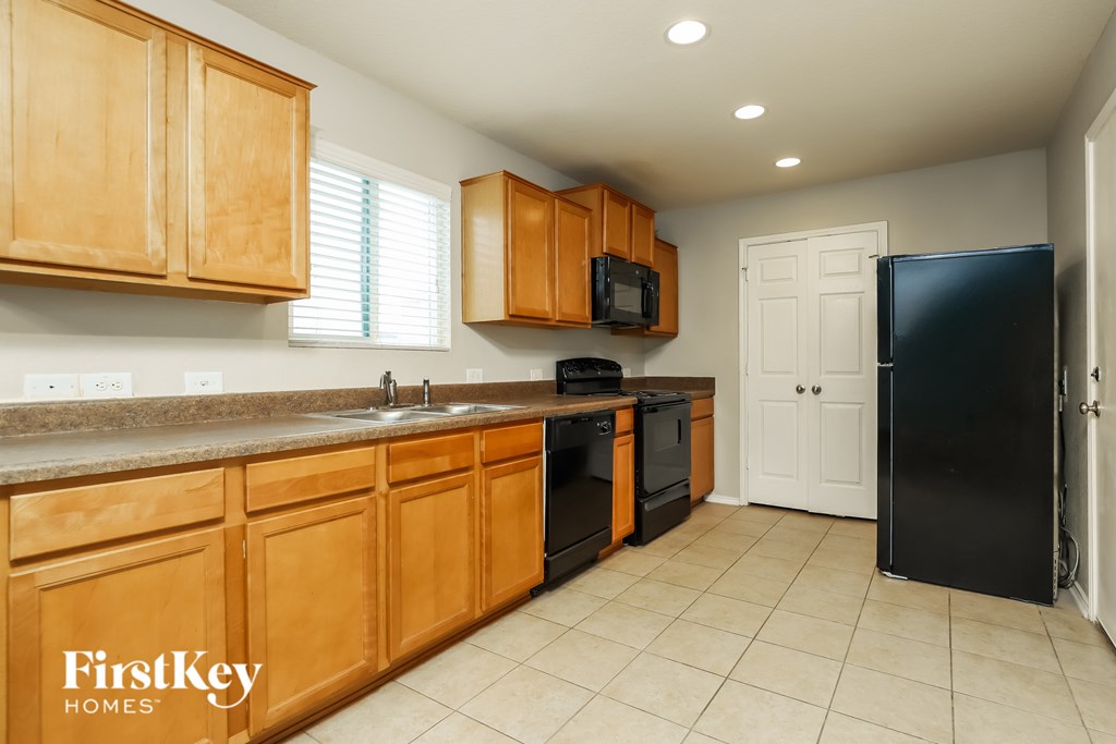 A kitchen with wooden cabinets and a black refrigerator.