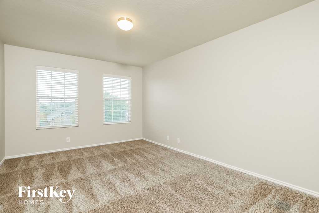 A room with a carpeted floor and two windows.