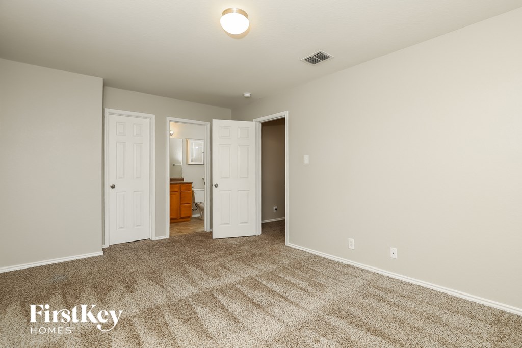 A carpeted room with a light on the ceiling and a FirstKey Homes logo on the bottom left.