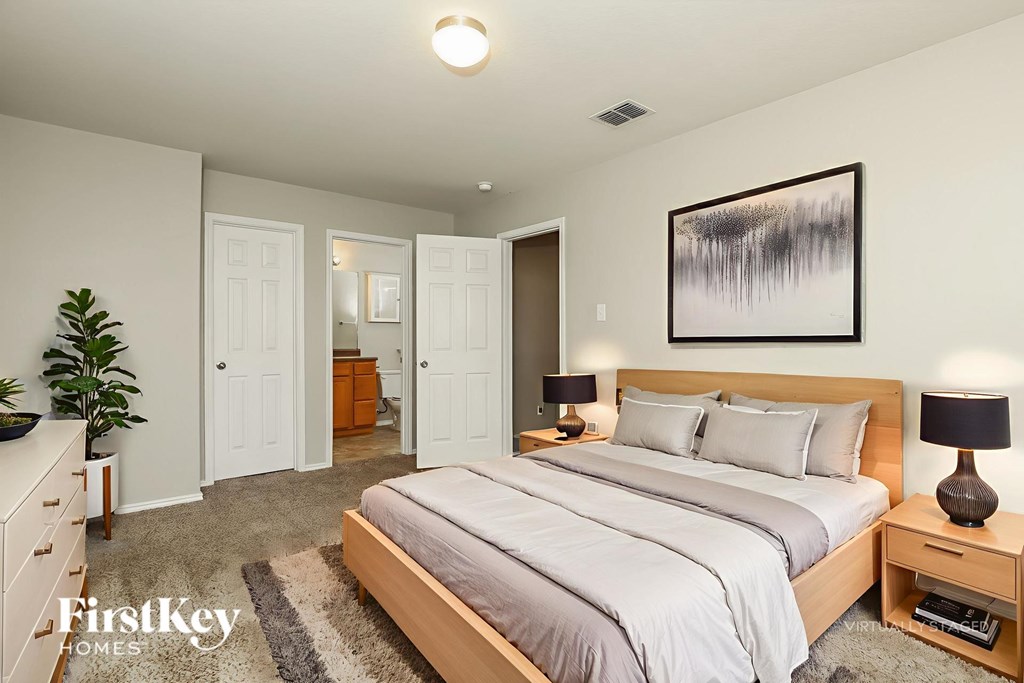 A bedroom with a large bed and a painting on the wall.
