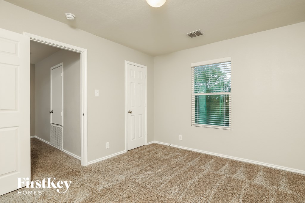 A room with a carpeted floor and a window with blinds.
