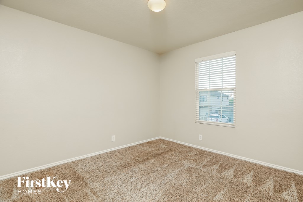 A room with a carpeted floor and a window with blinds.