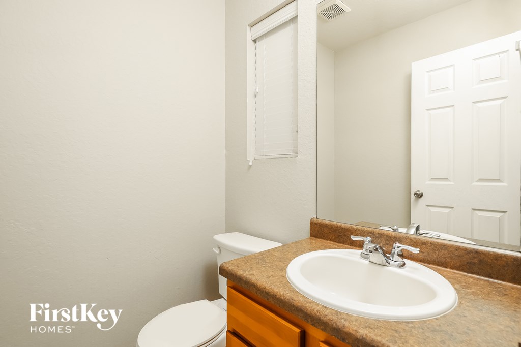 A bathroom with a sink, toilet and mirror.