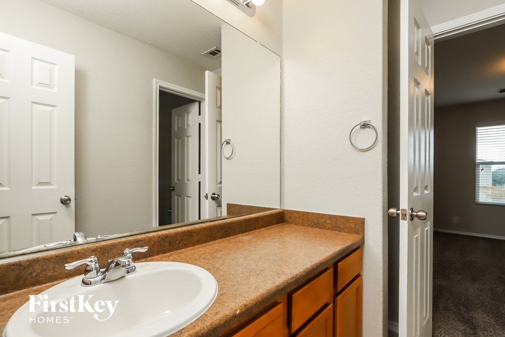 A bathroom with a sink, mirror, and a door.