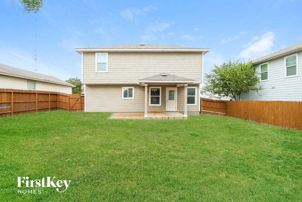 A house with a fence and a tree in the backyard.