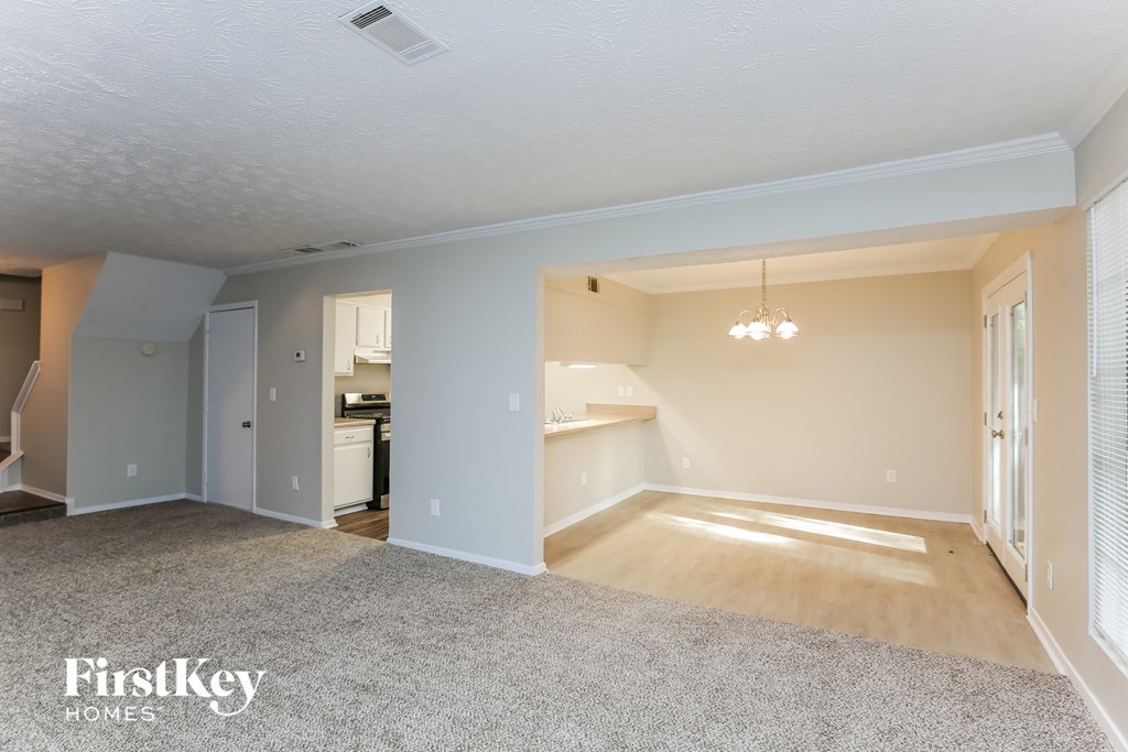 A spacious living room with a grey carpet and wooden flooring.