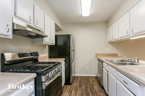 A kitchen with a black stove top oven and white cabinets.