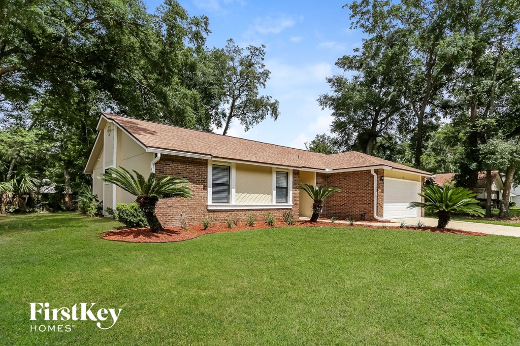 a small brick house with a lawn and palm trees