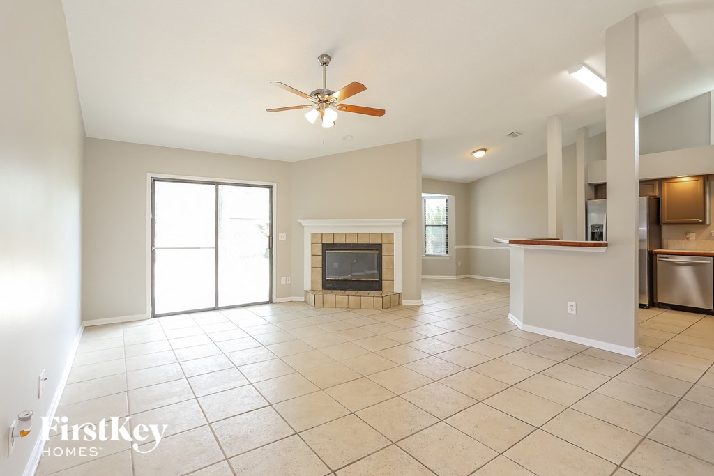 an empty living room with a fireplace and a ceiling fan