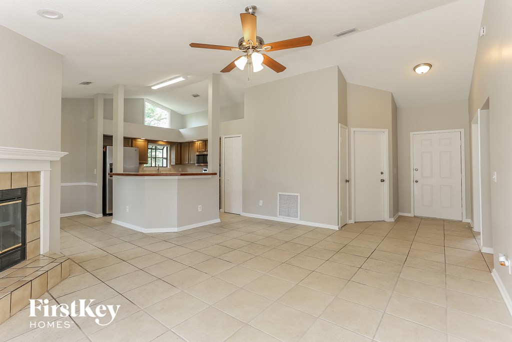 an empty living room with a fireplace and a ceiling fan