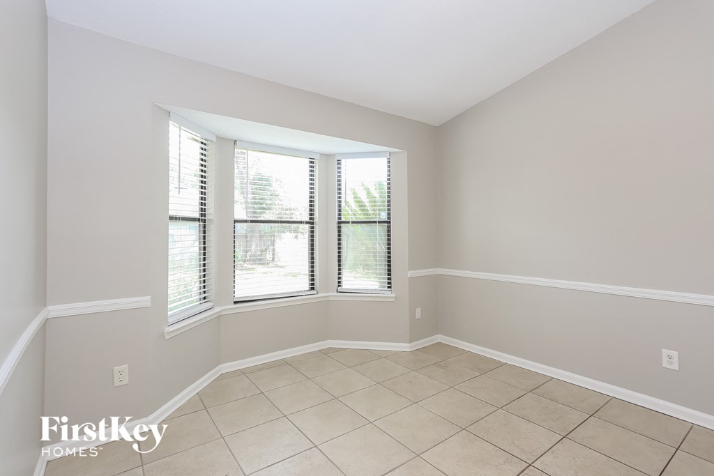 an empty living room with three windows and a tiled floor